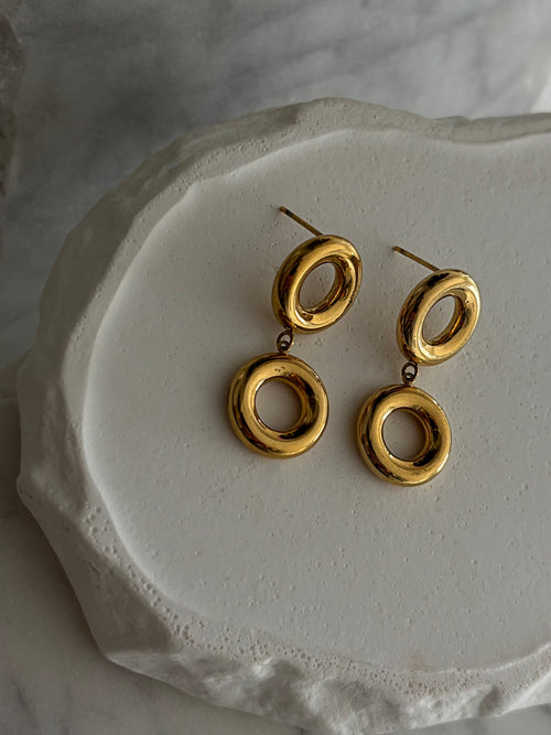 Gold circular earrings on a textured white surface