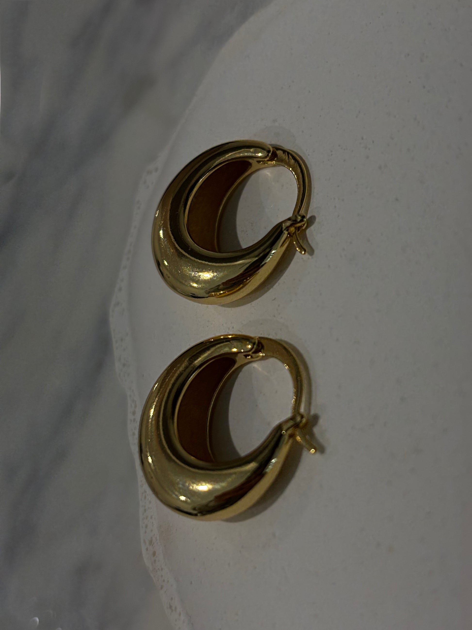 Pair of gold hoop earrings on a white surface