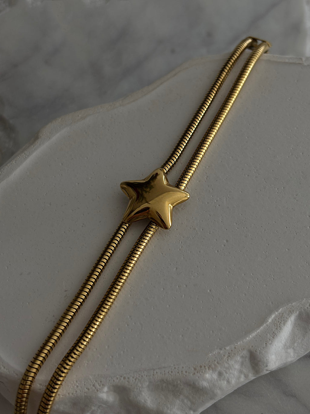 Gold star-shaped bolo tie on a marble surface