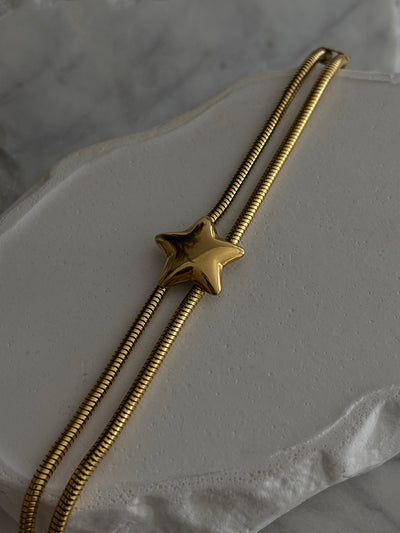 Gold star-shaped bolo tie on a marble surface
