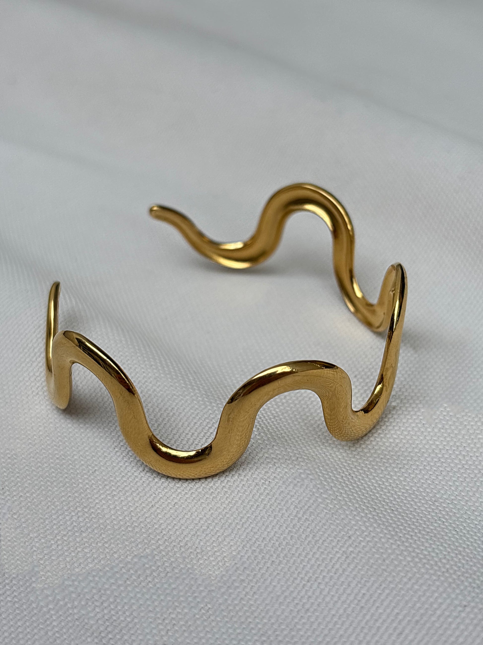 Gold wavy bracelet by EverLuxe on a light gray background | Waterproof and tarnish resistant