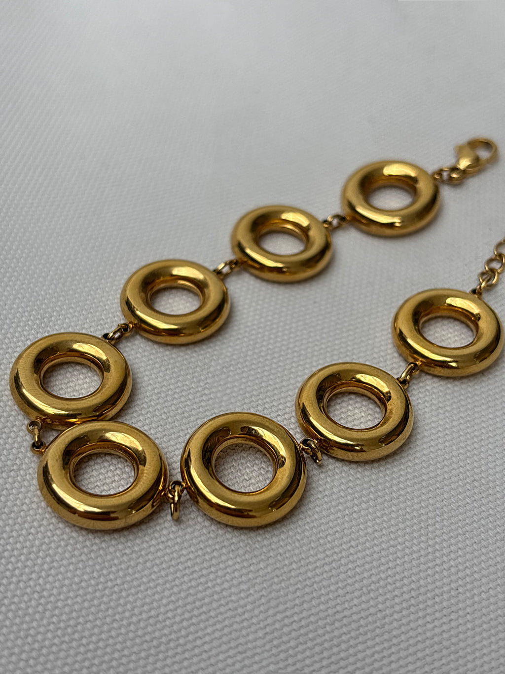 Gold bracelet with interlocking rings on a light gray background