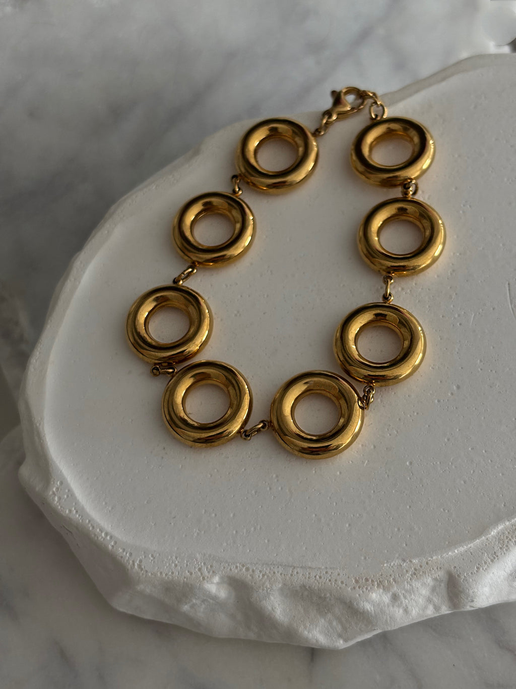 Gold everluxe bracelet on a white stone surface