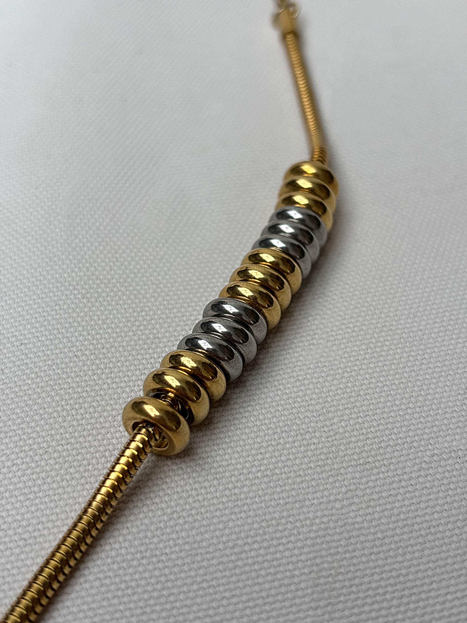 Gold and silver waterproof beaded necklace on a light gray background