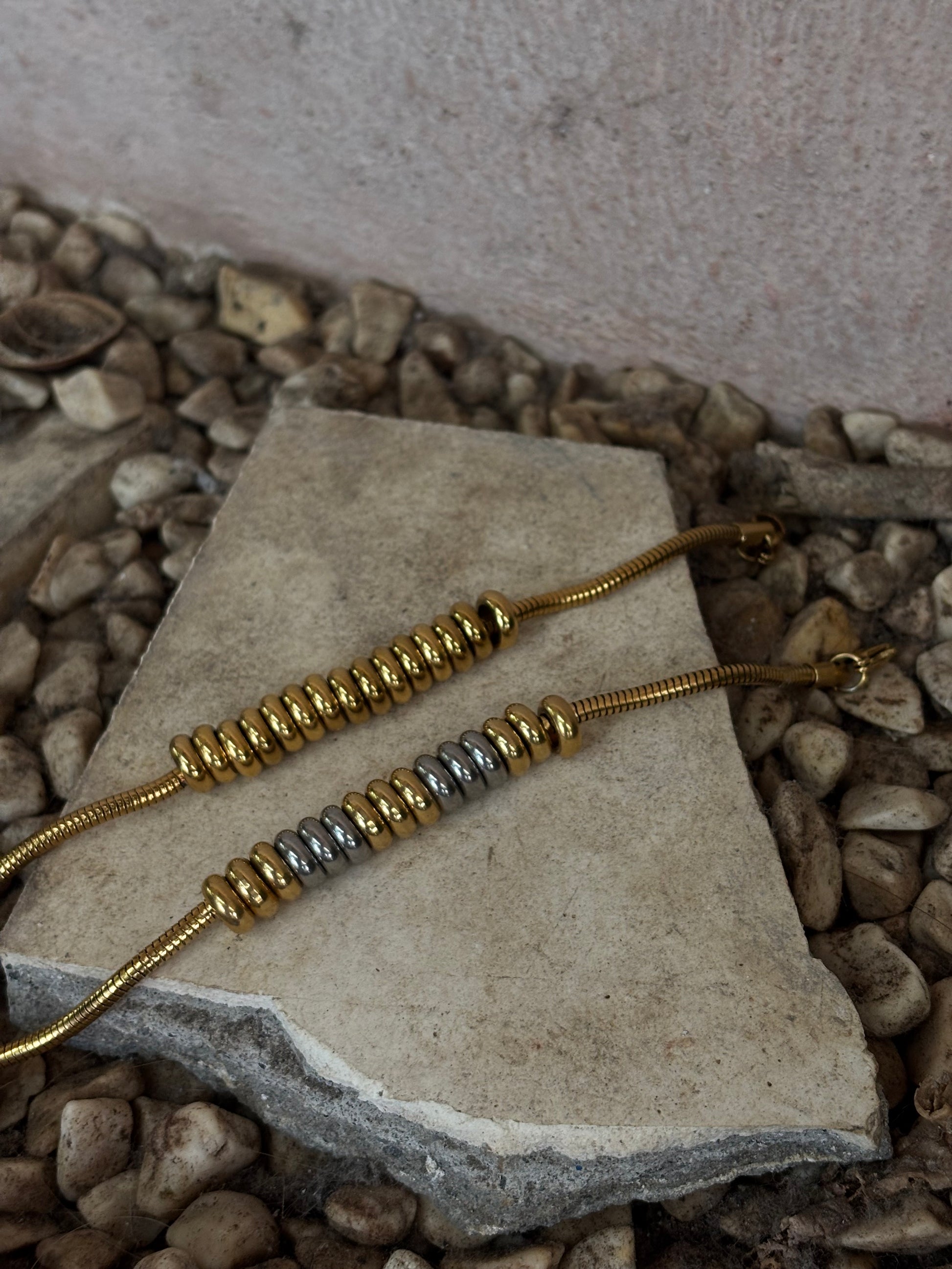 Gold and duo tone EverLuxe beaded necklace on a stone surface with a natural stone background