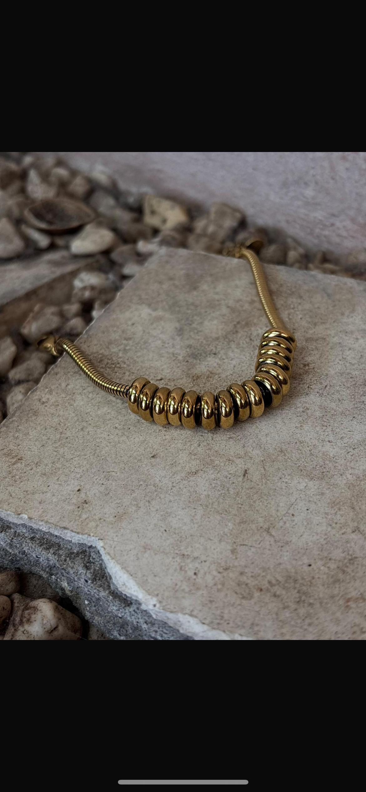 Gold tarnish resistant, hypoallergenic beaded necklace on a stone surface. 