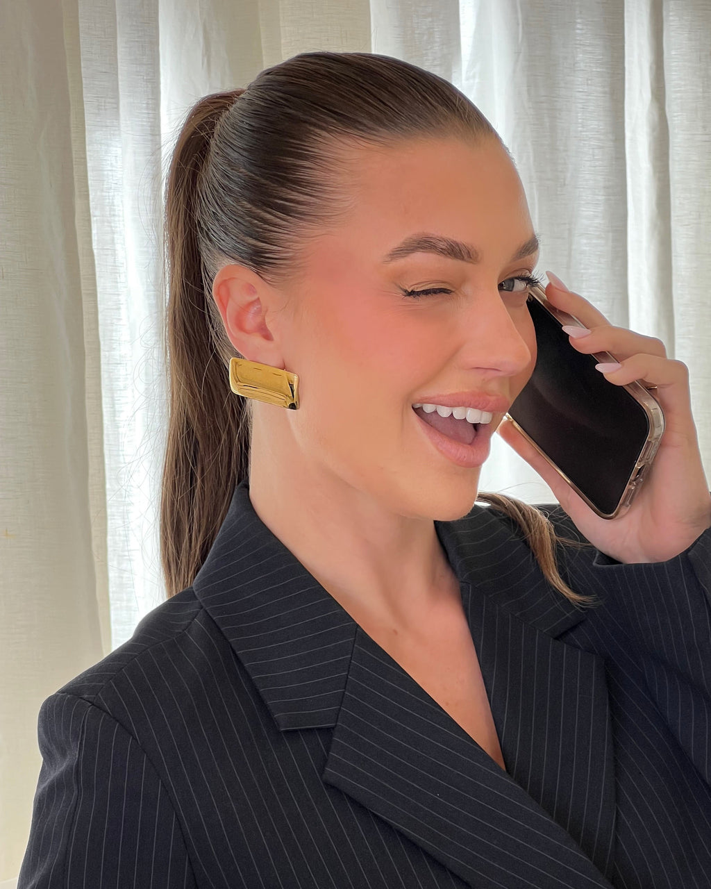 Model wearing gold statement stud earrings – waterproof & bold