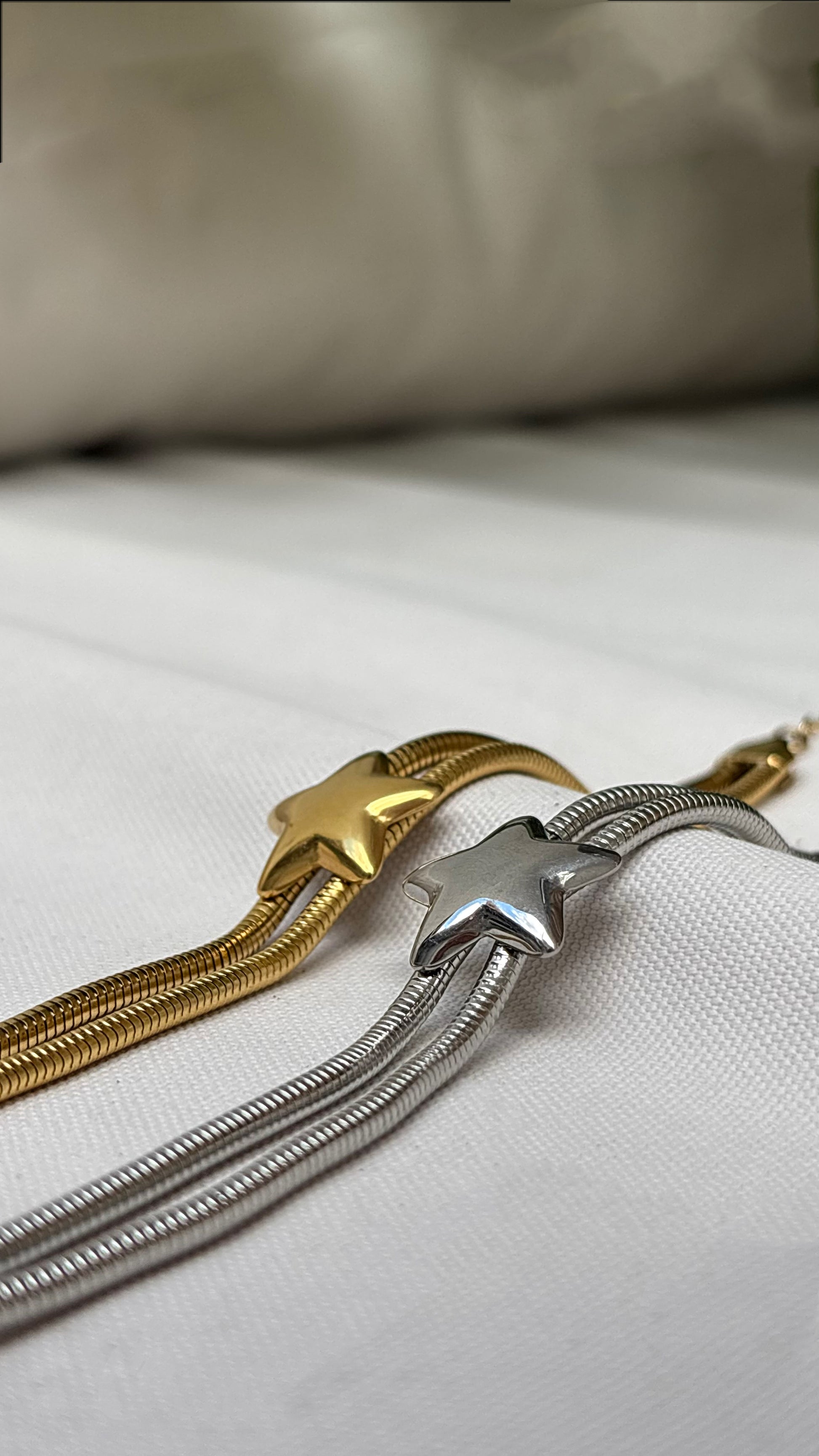 Gold and silver necklaces on a white fabric background by EverLuxe